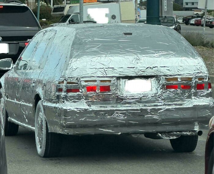 Car covered entirely in aluminum foil on city street showcasing outrageous car mods that took customization too far