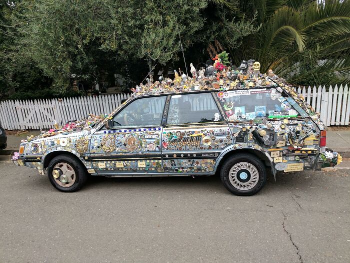 Car covered with numerous quirky decorations and toys showcasing one of the most outrageous car mods visible from the side.