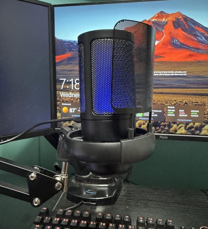 Black microphone with pop filter in front of dual monitors displaying a laptop screen, highlighting Prime Day electronic deals.