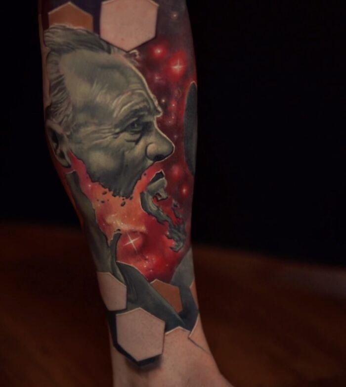 3D tattoo on arm by Jesse Rix featuring a realistic face and hexagonal shapes creating a portal to another world effect.