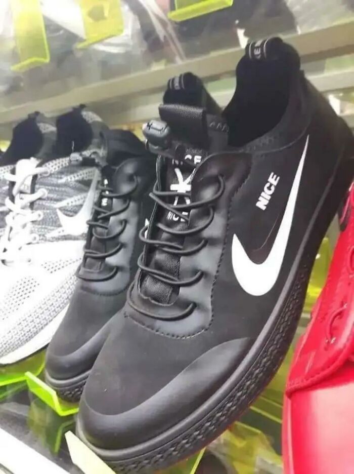 Black sneaker spoofing Nike logo with word NICE instead, displayed among other shoes, showing suspiciously unbothered branding.