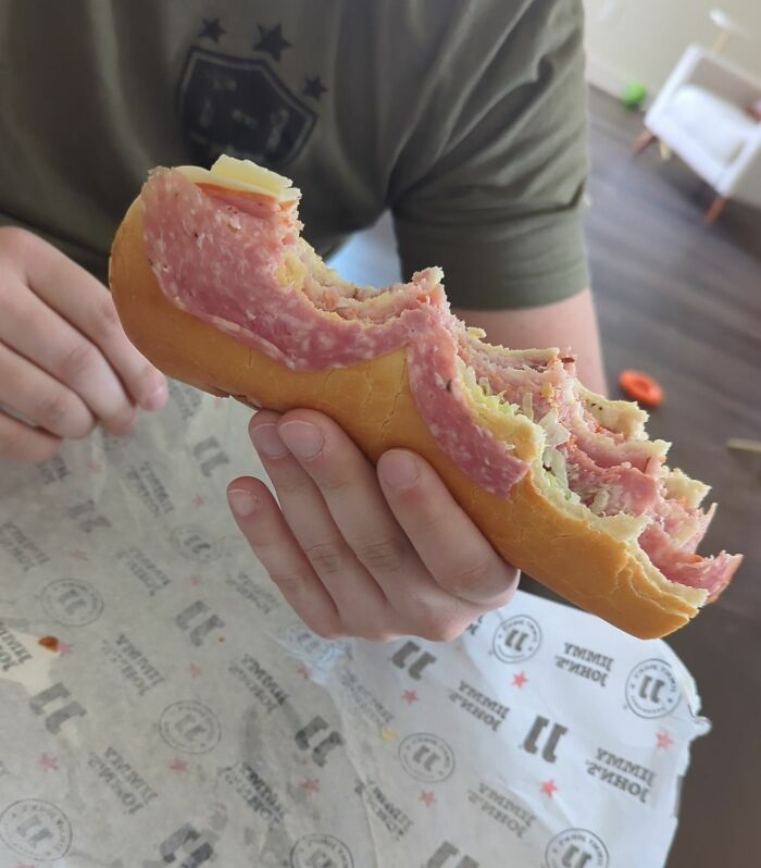 Partially eaten sandwich showing unevenly placed meat and cheese, illustrating cluelessness in some people’s partners.