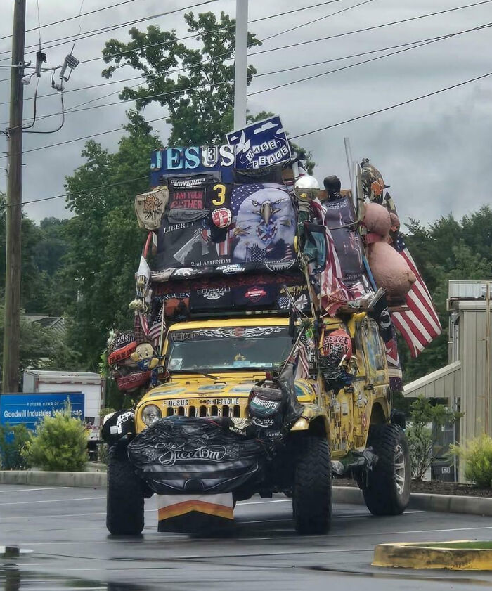 Yellow Jeep with extravagant and outrageous car mods, covered in signs, flags, and various decorations.