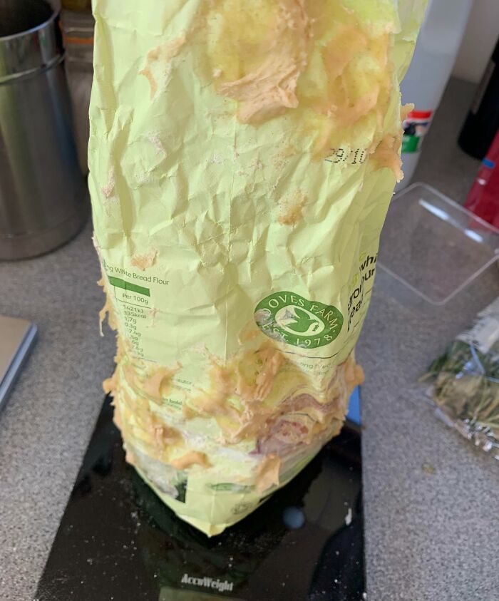 Crumbled flour bag covered in spilled peanut butter on a black kitchen scale, showing clueless partner mistake.