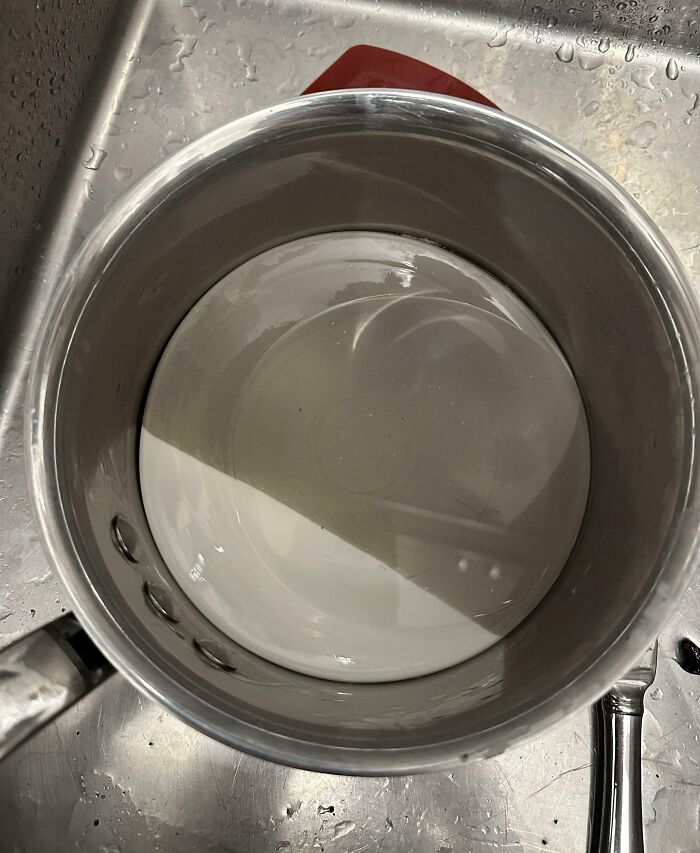 Stainless steel pot filled with water left in sink, illustrating clueless partner mistakes in everyday kitchen tasks.