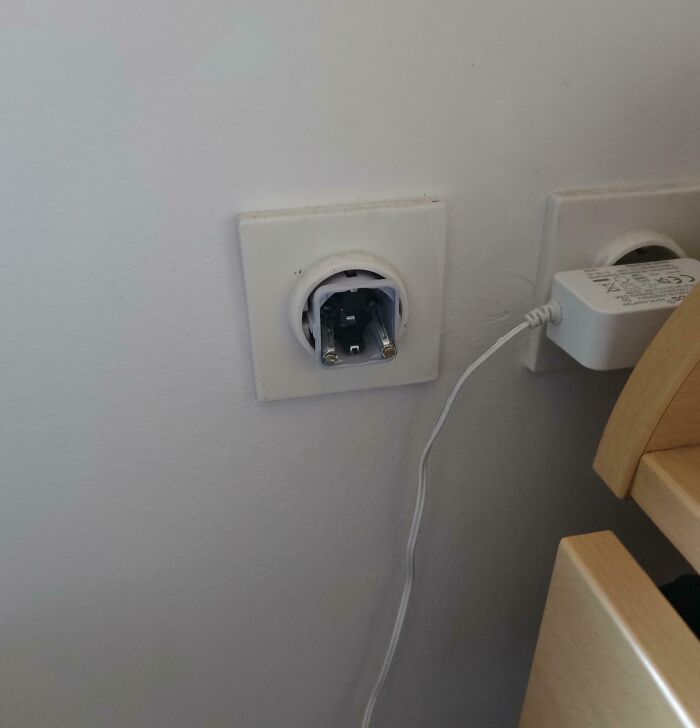 Plug adapter inserted incorrectly in wall socket, illustrating clueless partner moments in hilarious photos.