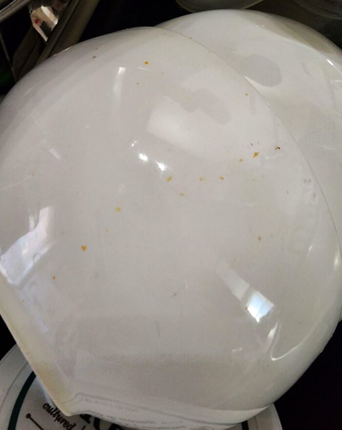 Two dirty white plates stacked, showing a clueless partner's messy dishwashing skills in a humorous situation.