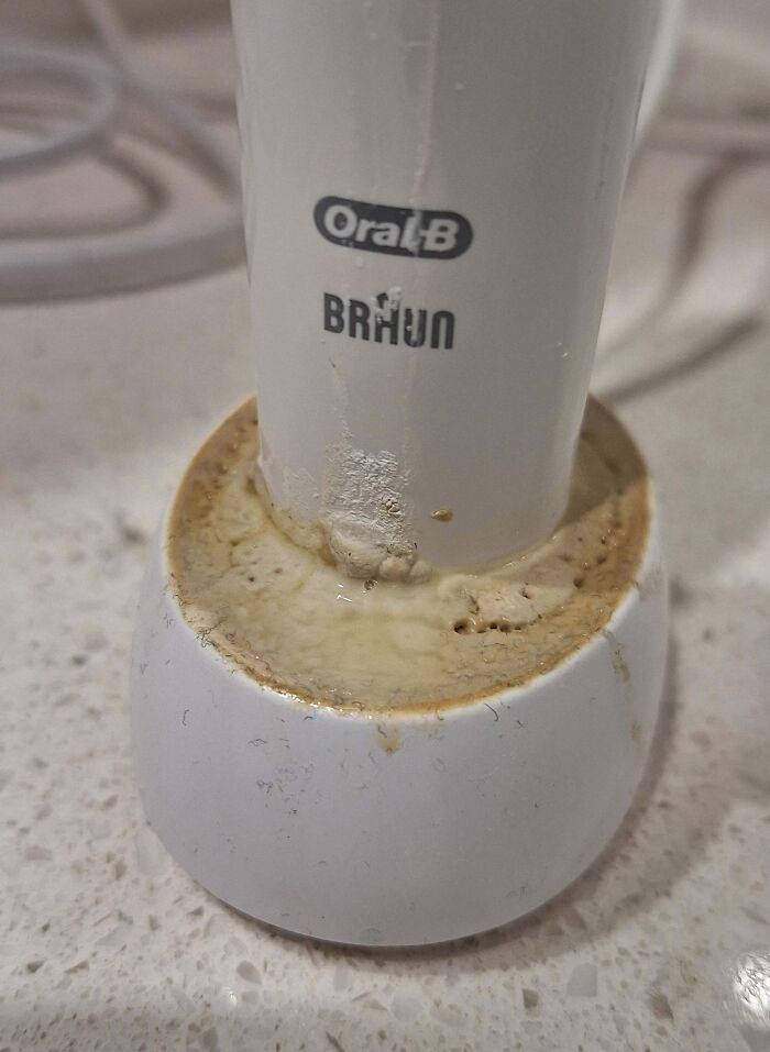 Oral-B electric toothbrush charger base covered in grime and dirt showing clueless partner neglect in hygiene.