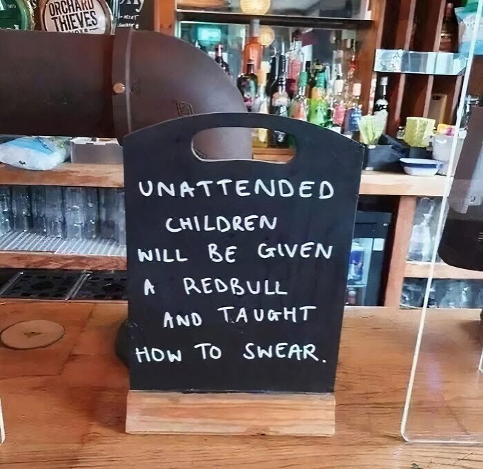 Funny work meme on a chalkboard warning unattended children will be given Red Bull and taught how to swear.