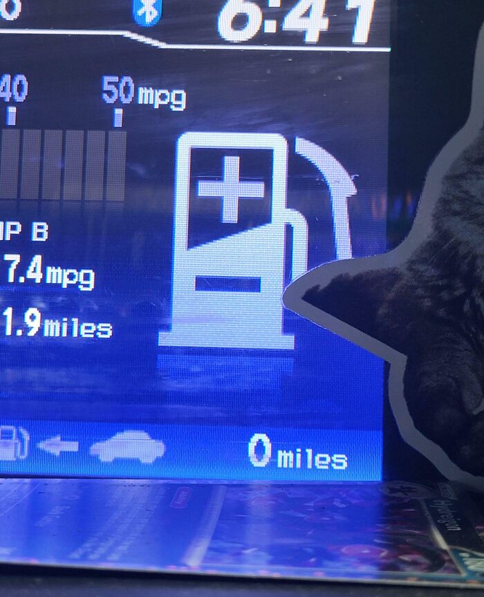 Car dashboard showing zero miles to empty with a cat sticker nearby, illustrating clueless partner humor.
