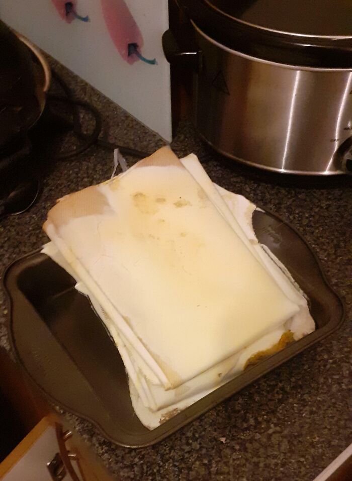 Stack of stained, unused napkins placed in a baking pan on kitchen counter, showing clueless partner mistake.