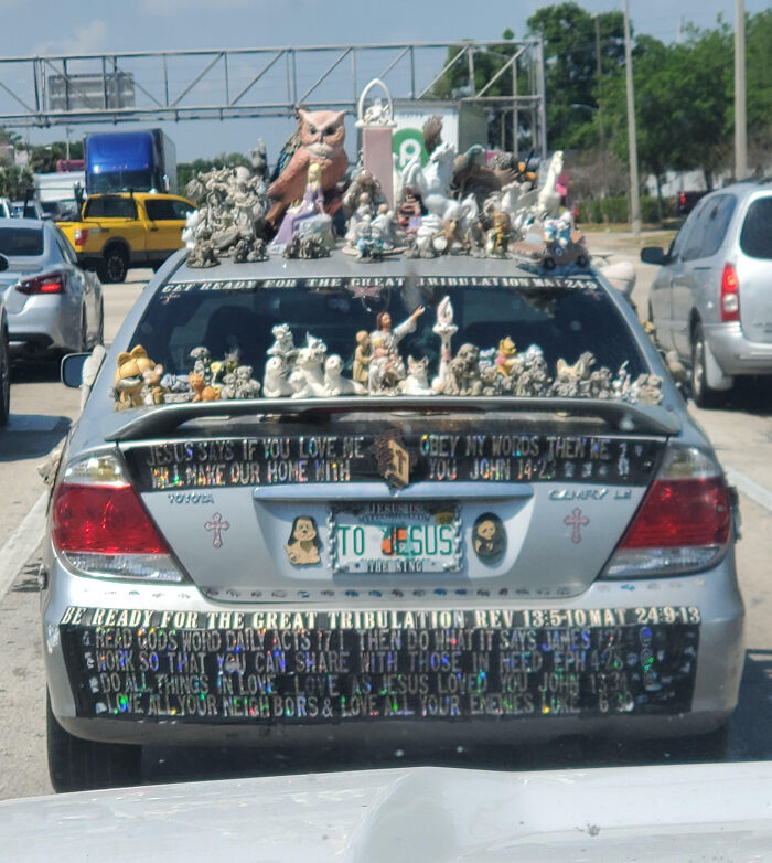 Silver car covered with religious figurines and decals, an example of outrageous car mods that took things way too far.