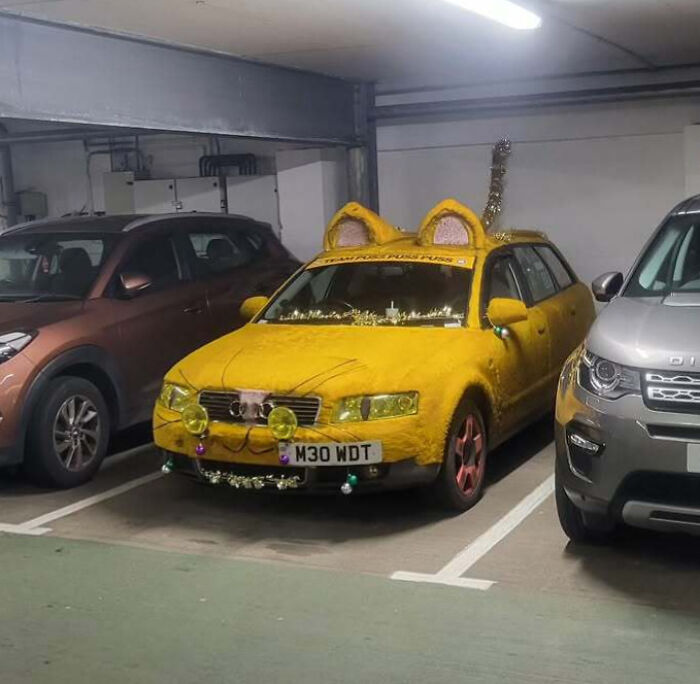 Yellow car covered in fur with cat ears, whiskers, and decorations, an example of outrageous car mods.