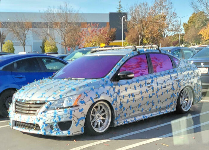 Car covered in 3D hammer-shaped car mods with purple tinted windows in a parking lot, showcasing outrageous car mods.