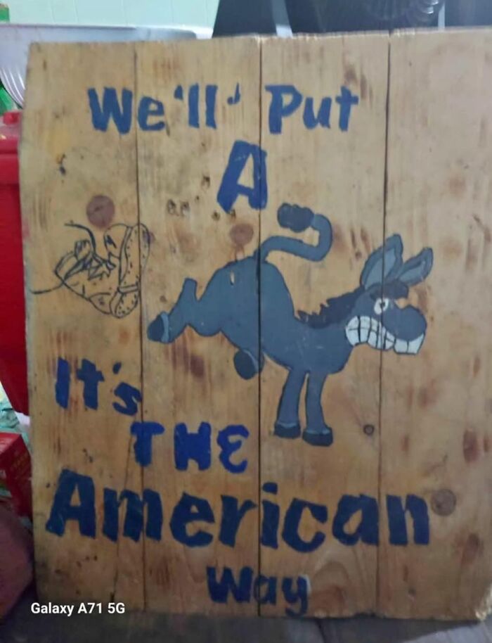 Wooden board with badly painted donkey and text reading we'll put a A it's the American way, showcasing horrible crafts.