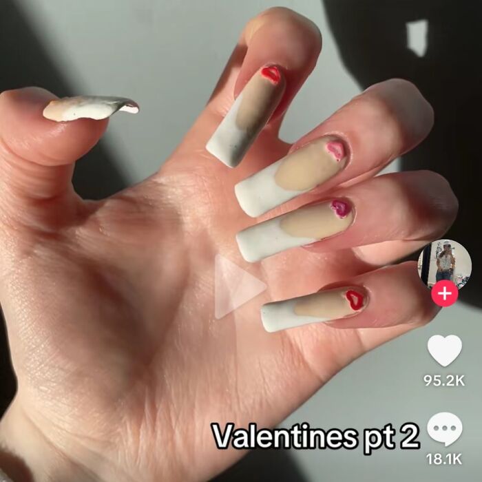 Close-up of poorly done nail art with uneven white tips and imperfect red heart shapes, illustrating horrible crafts.