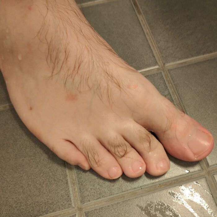 Close-up of a mildly interesting hairy foot on tiled floor, an unexpected detail captured in everyday life.