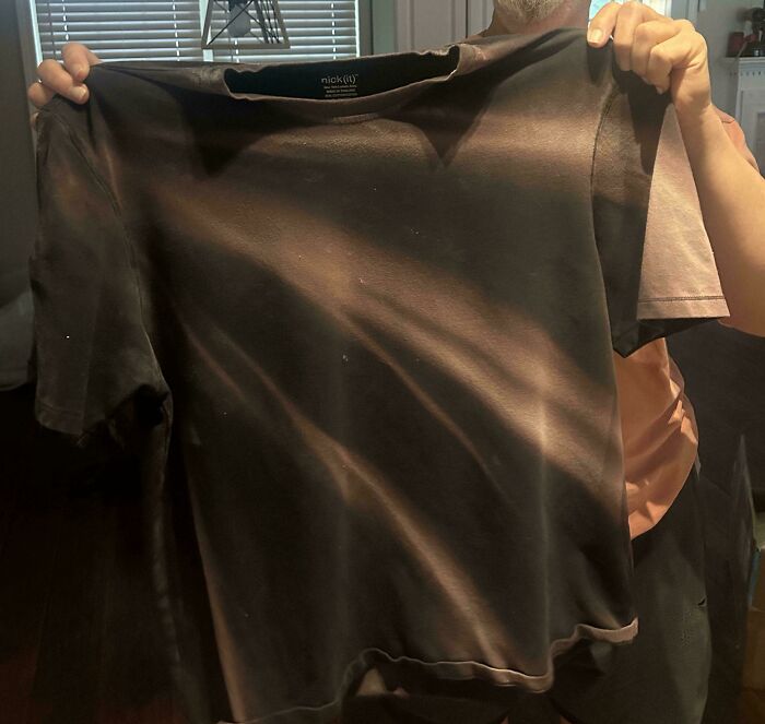 Faded tie-dye shirt held up by person showing unique patterns from wear and sunlight in a mild interesting discovery.