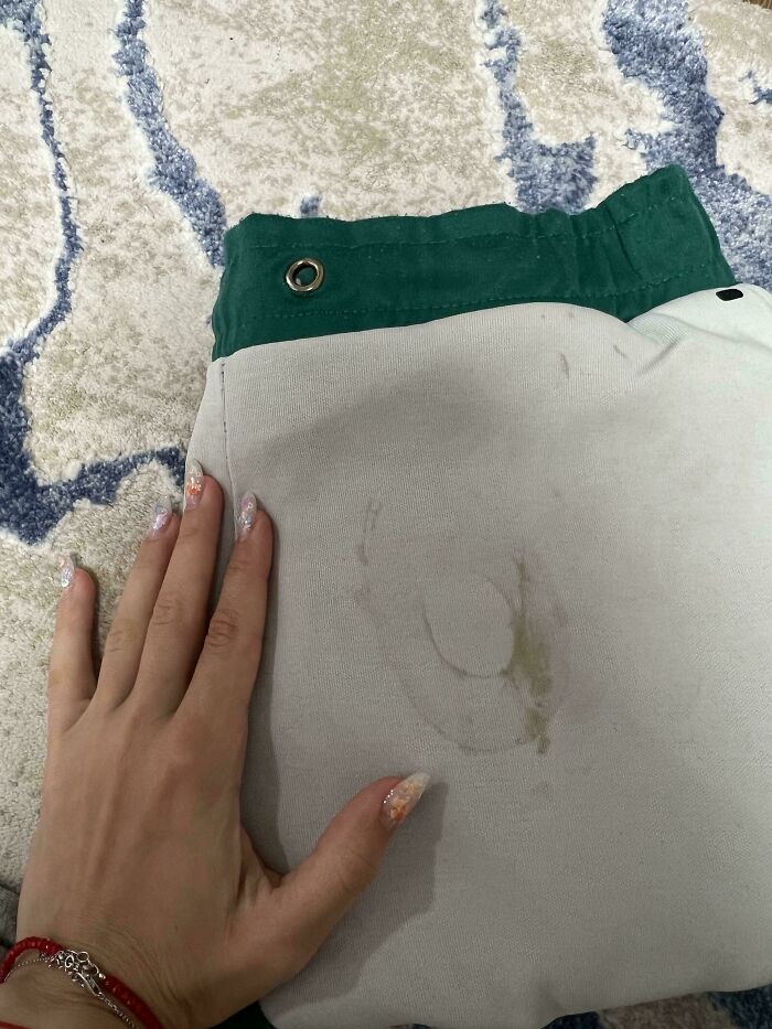 Hand with decorated nails touching pants with a faint stain, a mildly interesting find shared by people online.