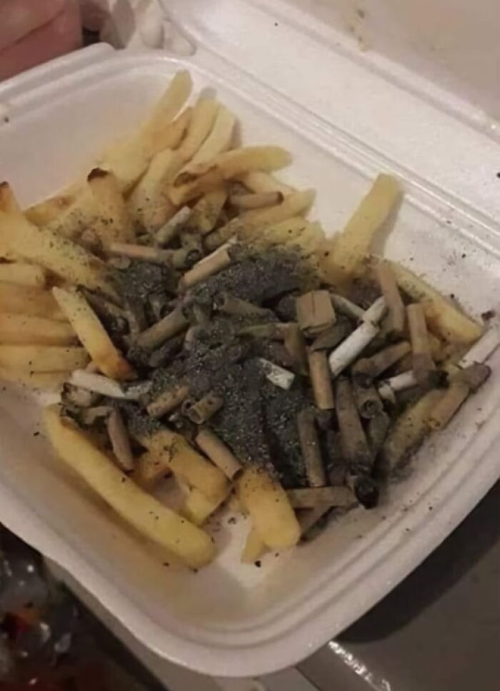 Takeout container with French fries covered in cigarette butts and ashes, a cursed food picture that might make you go eeeeeuw