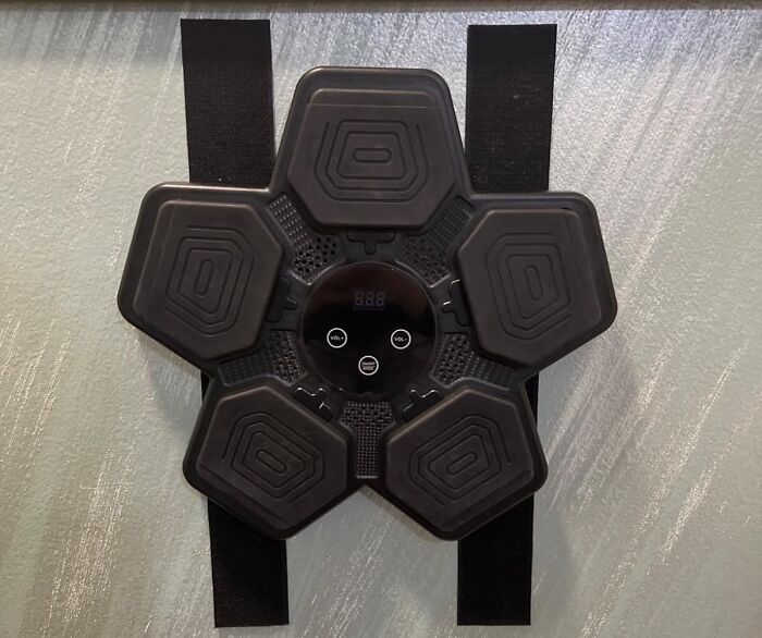 Black six-pad electronic muscle stimulator with adjustable straps resting on a light surface, Prime Day treasure product.