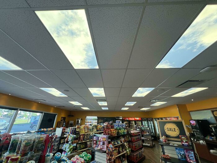 Convenience store interior with ceiling lights designed to look like bright blue sky with clouds, showing mildly interesting design.