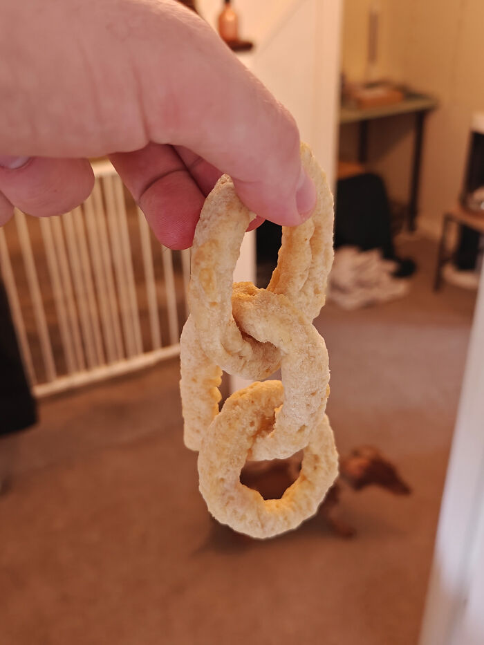 Hand holding three linked snack rings indoors showing a mildly interesting connection of snacks.