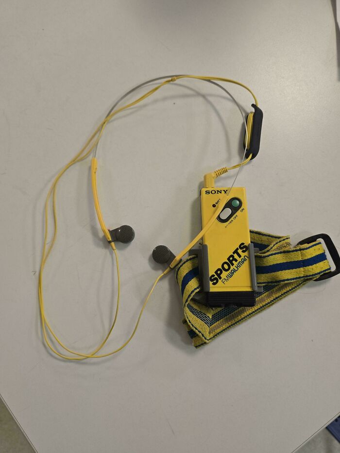 Vintage yellow Sony Sports FM/AM Walkman with matching yellow earbuds and striped wristband, mildly interesting find shared by people.