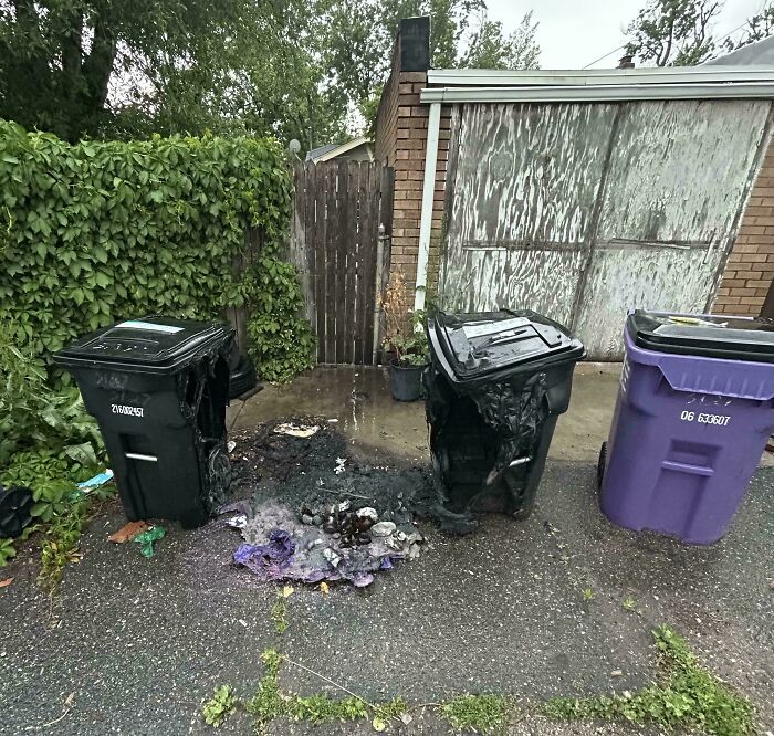 Three outdoor trash bins with two melted from fire, showing a mildly interesting damaged recycling scene in a driveway.
