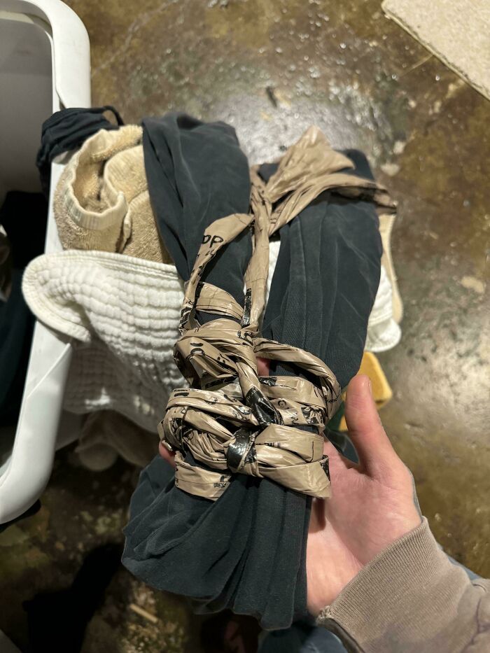 Hand holding an umbrella tightly wrapped with tape in a funny unfortunate situation of forgetting something.