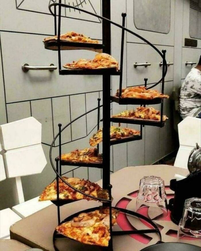 Pizza slices served on a spiral staircase stand, showcasing meals presented in unholy and unexpected ways.