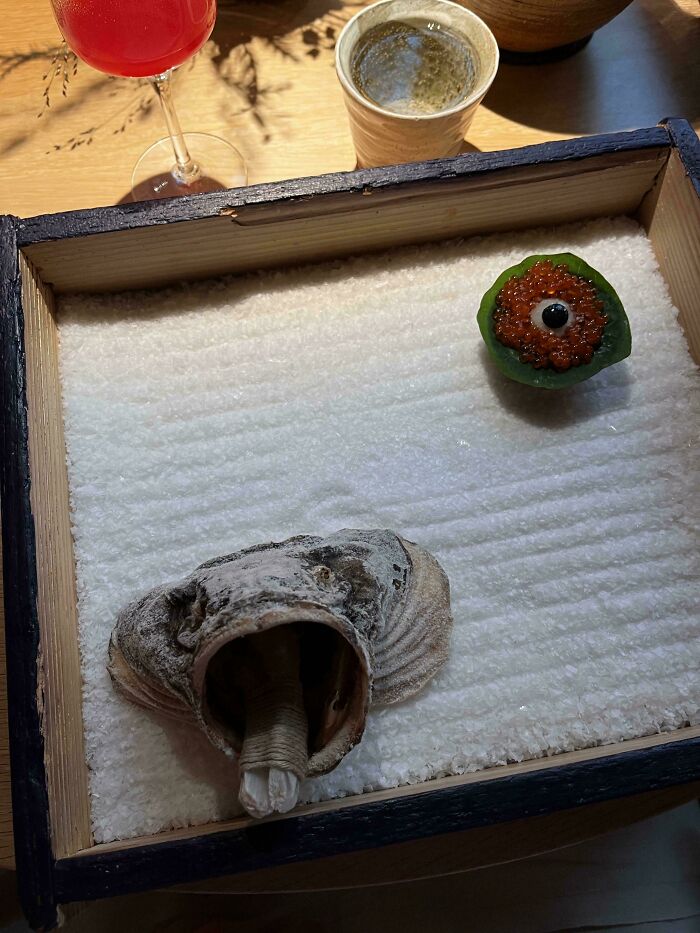 Unholy meal presentation featuring seafood and garnish served inside a wooden box on a bed of salt.