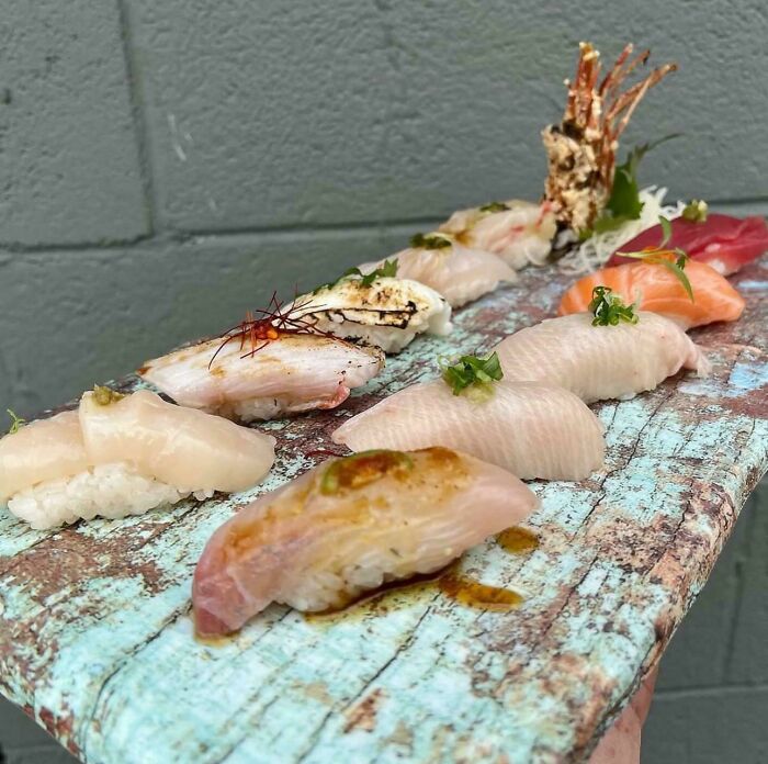 Variety of sushi pieces served on a rustic wooden board in an unexpected unholy meal presentation.