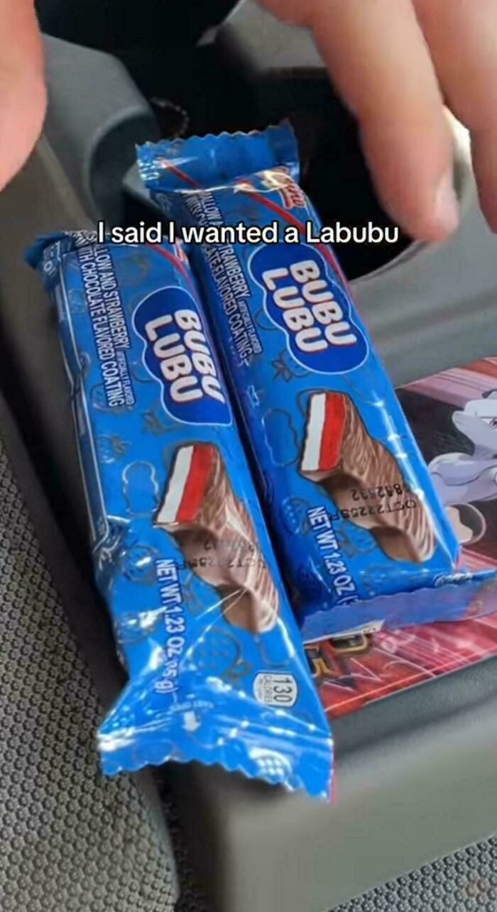 Two Bubu Lubu candy bars in blue wrappers in a car, with text about wanting a Labubu doll meme online.