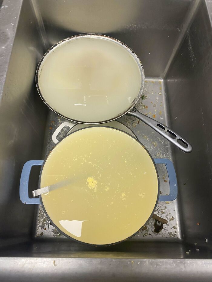 Two large pots filled with liquid left in a kitchen sink, showing an epic work fail with food cleanup.