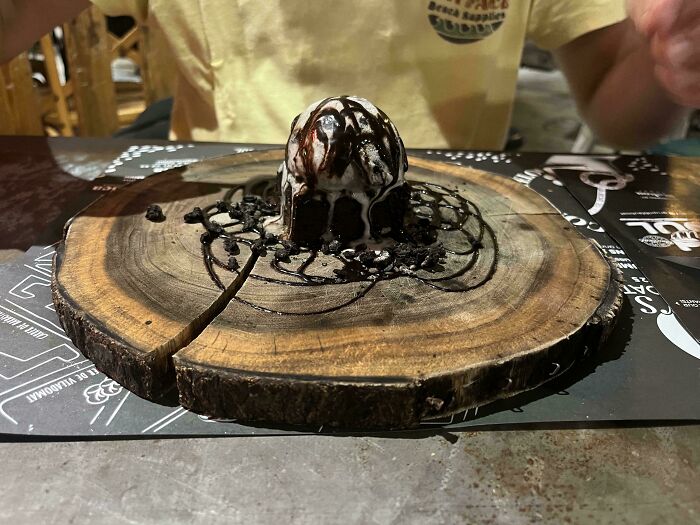 Dessert served on a wooden slab with chocolate sauce drizzled, showcasing unusual meals served in unholy ways.