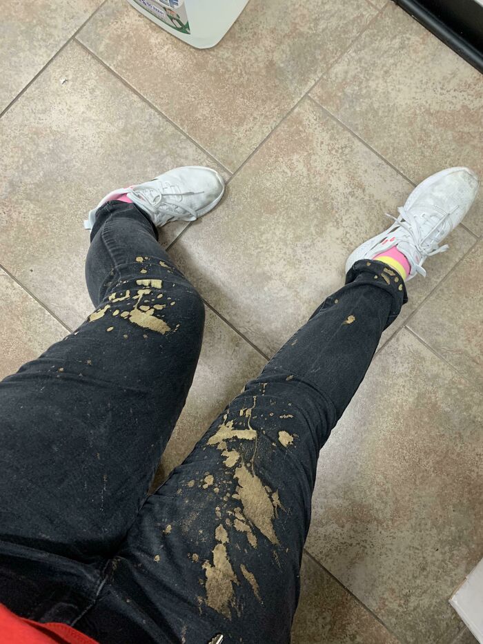 Person wearing white shoes and black pants with large brown stains on legs, showing an epic work fail moment.