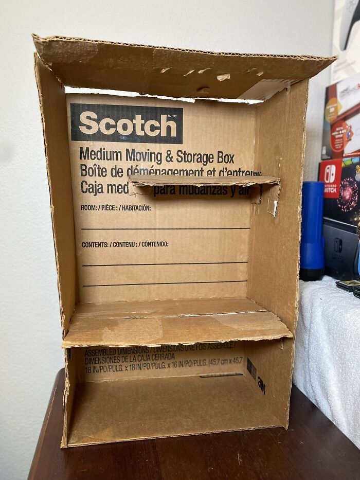 Cardboard box repurposed with cut shelves showcasing creative redneck engineering and practical MacGyver-style construction.