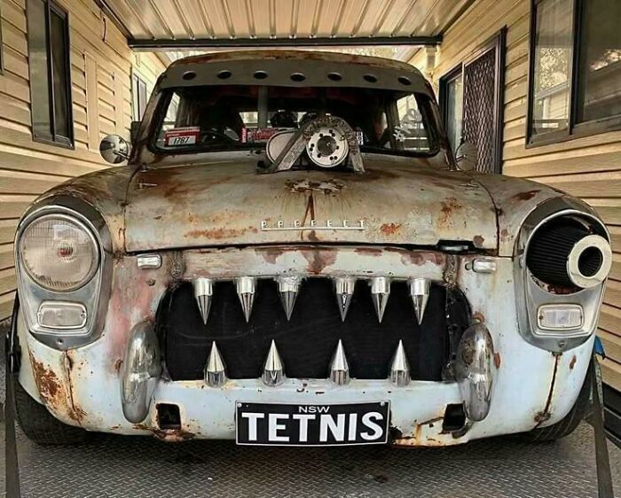 Rusty vintage car modified with spikes and a custom air intake, showcasing creative redneck engineering and MacGyvering skills.