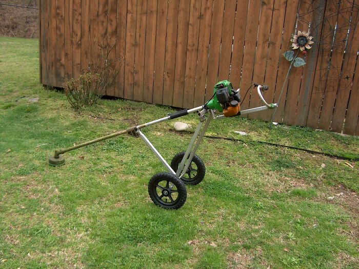 Homemade wheeled lawn trimmer featuring creative redneck engineering and inventive MacGyver-style modification outdoors.