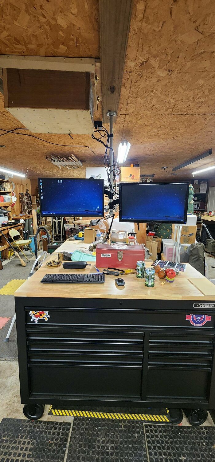 Dual computer monitors mounted on a toolbox workbench in a workshop showing redneck engineering creativity.
