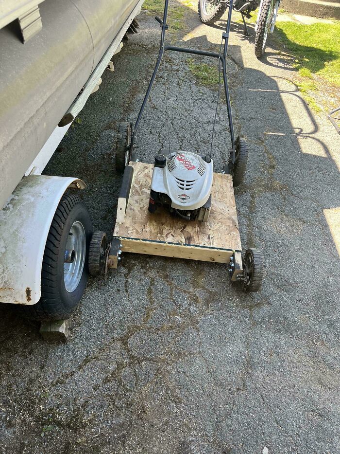 Homemade lawnmower with a DIY wooden base and metal frame showing creative redneck engineering.