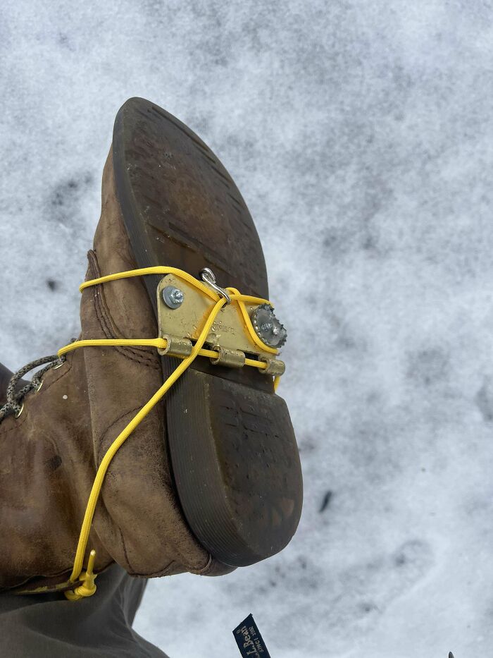 Boot with homemade traction device attached using yellow cords, an example of inventive redneck engineering in snowy conditions.
