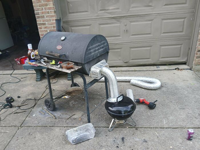 Portable grill modified with flexible ducting and metal components demonstrating creative redneck engineering.