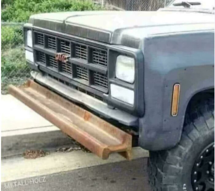 Front view of GMC truck with a large custom-made rusty metal bumper as an example of redneck engineering creativity.