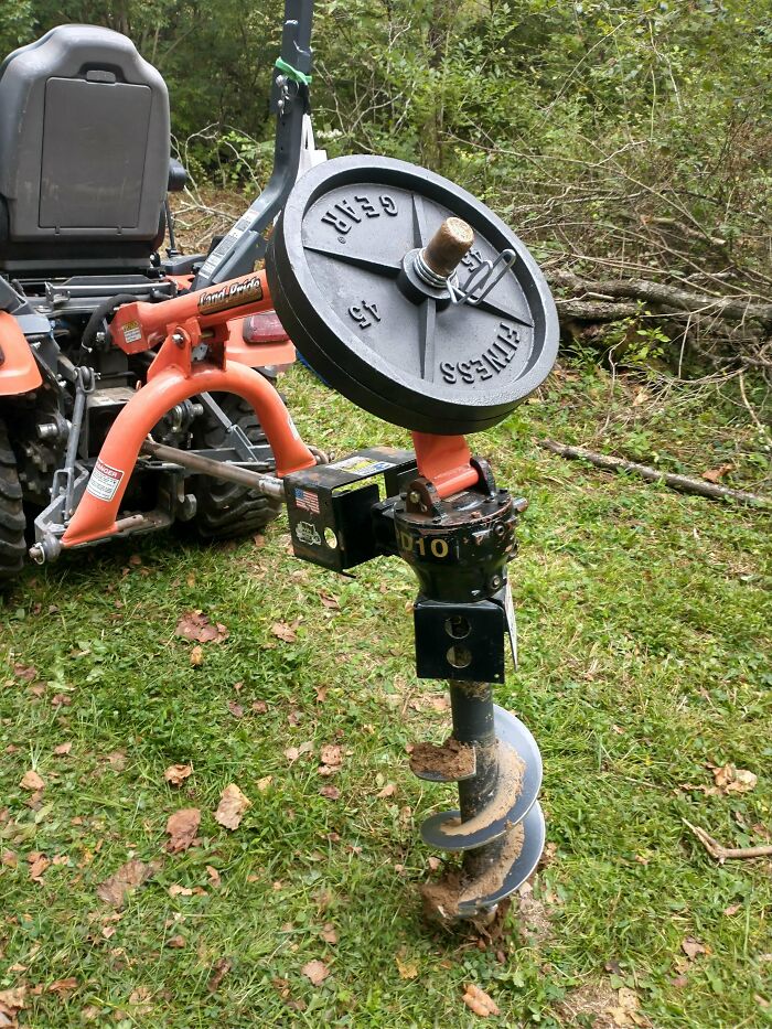 Tractor with a DIY redneck engineering auger attachment using a weight plate for creative MacGyvering outdoors.