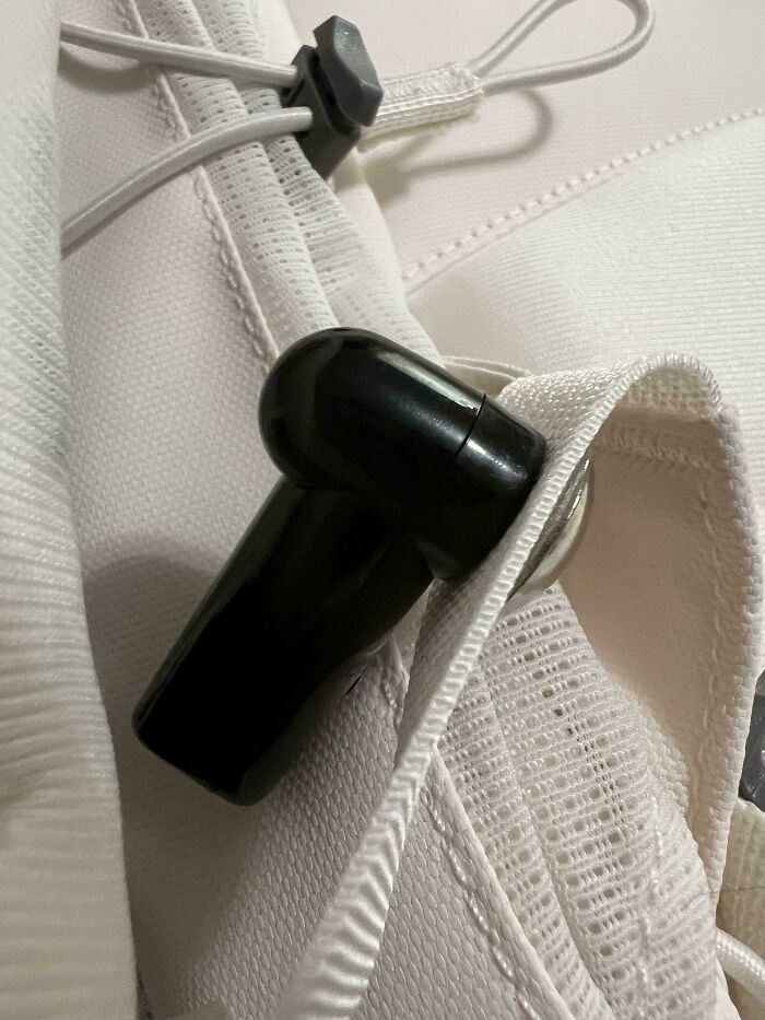Black wireless earbud stuck inside white fabric pocket illustrating funny unfortunate situations of forgetting items.