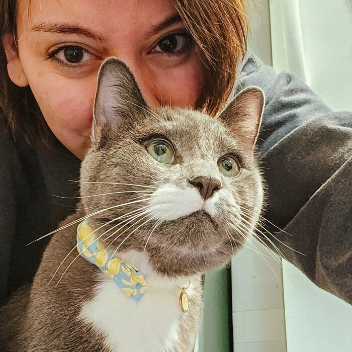Woman posing closely with her cat wearing a bow tie, showing a clever way to help a cat taking pills.