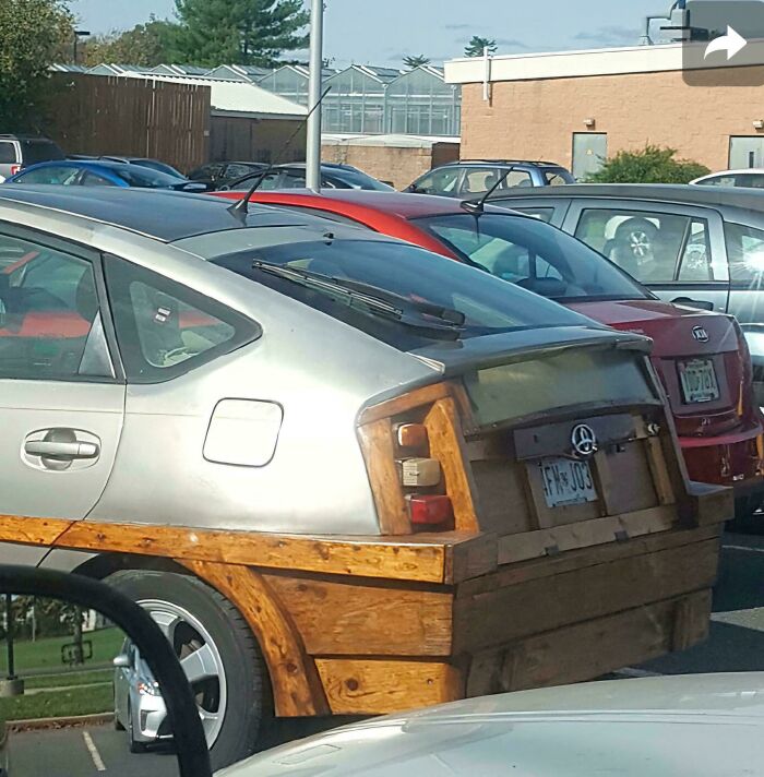 Silver car with wooden panels and modifications showcasing creative redneck engineering in a parking lot with other vehicles.