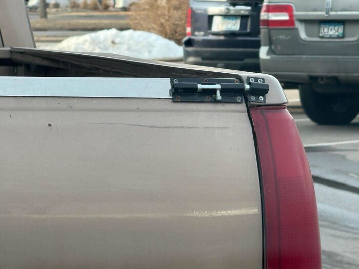 Pickup truck tailgate secured with a metal latch as an example of redneck engineering creative MacGyvering.